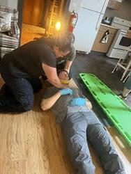 Two EMS students work on a third EMS student lying on the ground in a neck brace during an EMS course